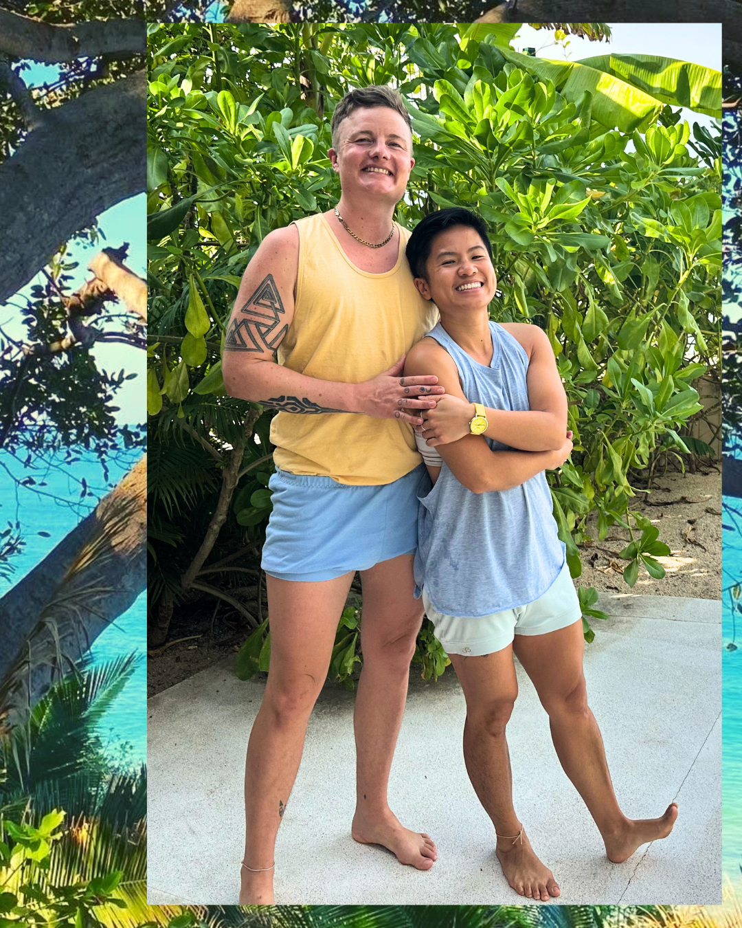 Avery Kalapa and G Tiarachristie, Queer Trans Retreat leaders, smiling and standing together by tropical plants, wearing Iyengar Yoga clothes after class.